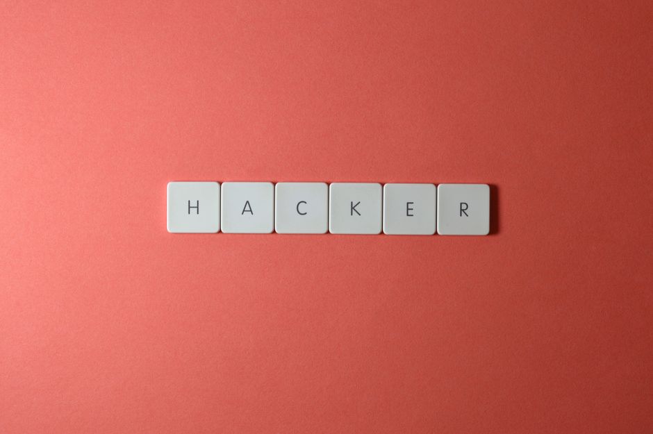 Close-up of the word 'HACKER' made with letter tiles on a red background, emphasizing cybersecurity.