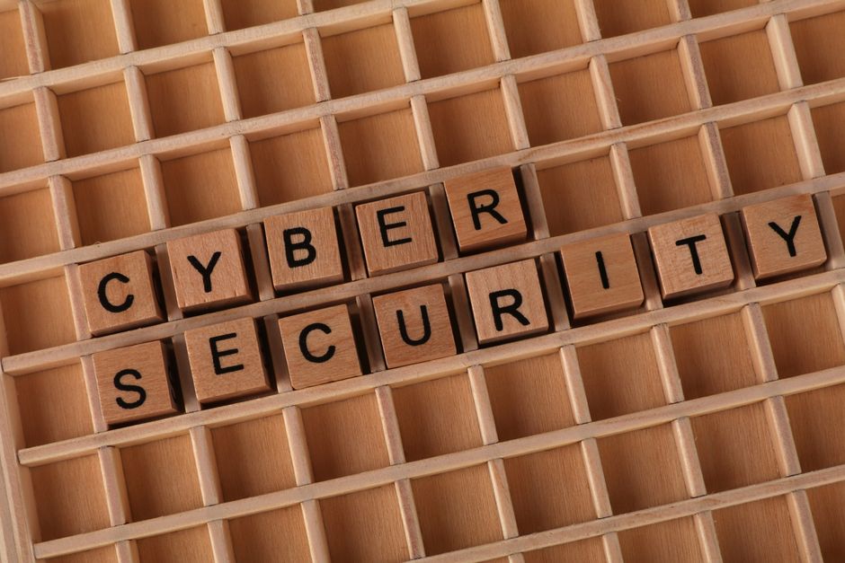 Wooden blocks spelling 'Cyber Security' on a wooden grid background.