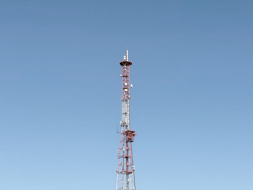 A tall communication tower set against a cloudless blue sky, symbolizing modern telecommunications.