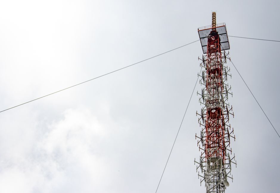 A towering red and white telecommunications structure reaching into a cloudy sky, highlighting modern technology.