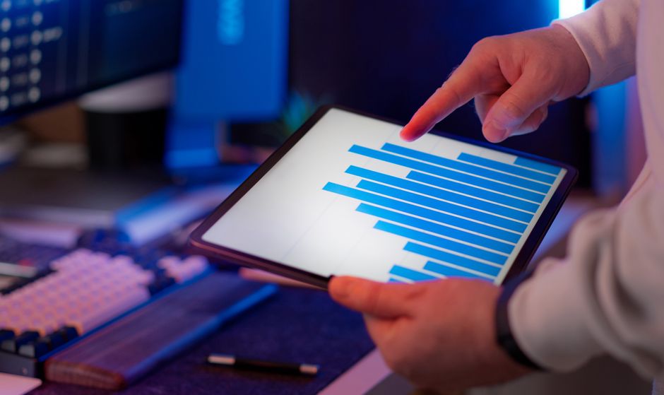 Business professional analyzing bar chart on tablet in office setting, highlighting data insights.