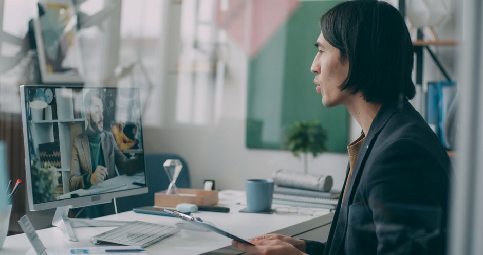 A professional engaged in a video conference in a modern office setting.