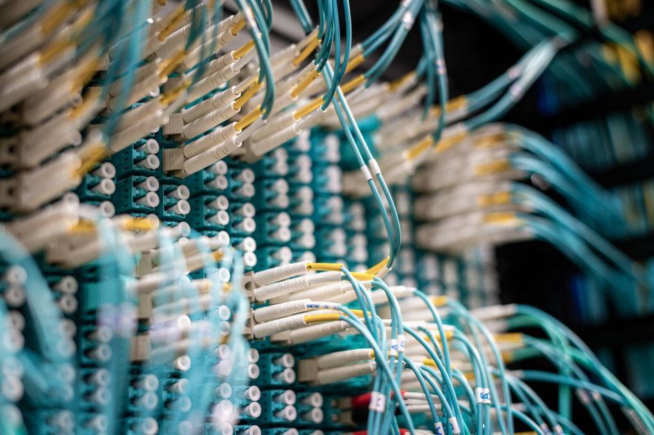 From below of fiber optic switch with sockets and connected rubber cables on blurred background