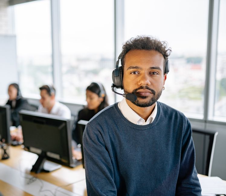 Confident call center agent wearing headset in modern office setting.