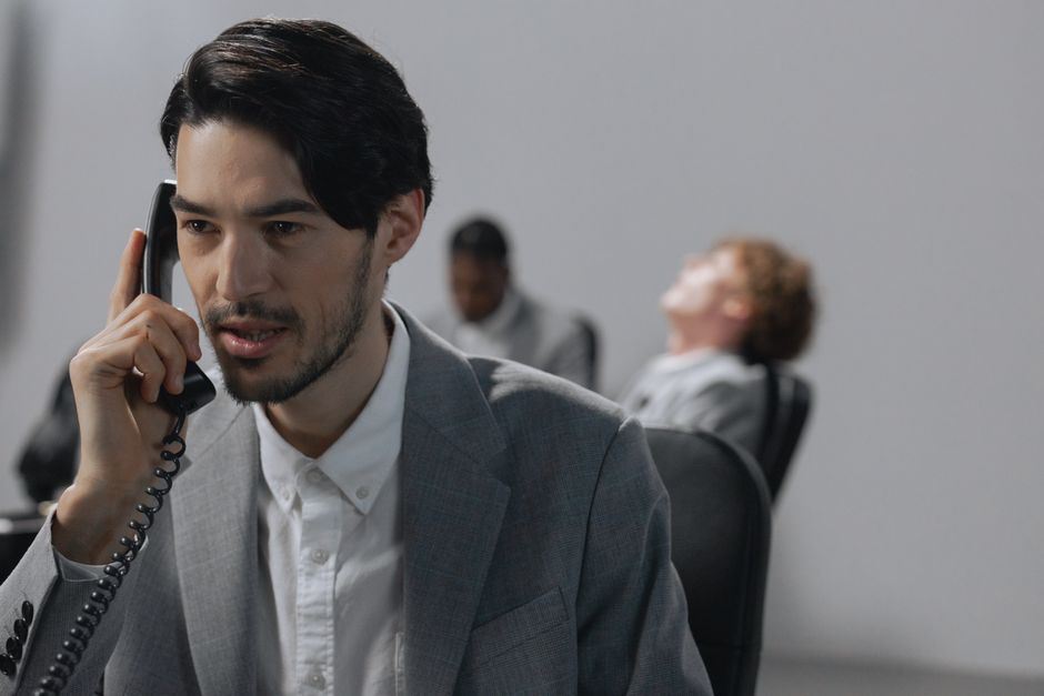 Young businessman in gray suit on phone, emphasizing office communication.