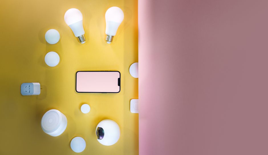 Flat lay of smart home devices with vibrant pink and yellow gradient background.