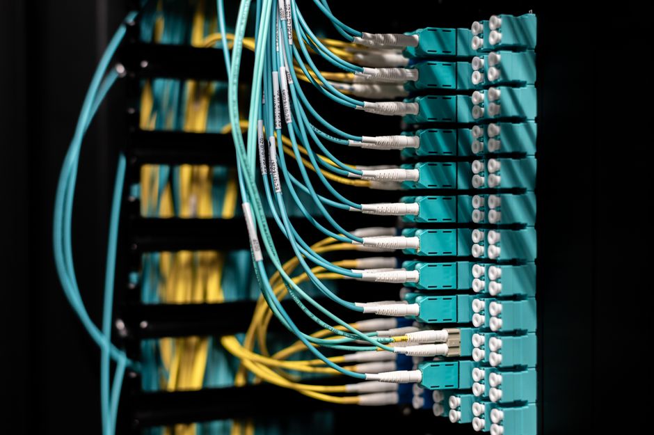 Closeup of electronic device with colorful wires installed in rows in communications room on blurred background in dark studio inside