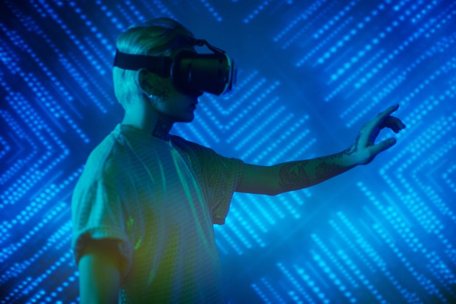 Person immersed in virtual reality with a neon blue background.